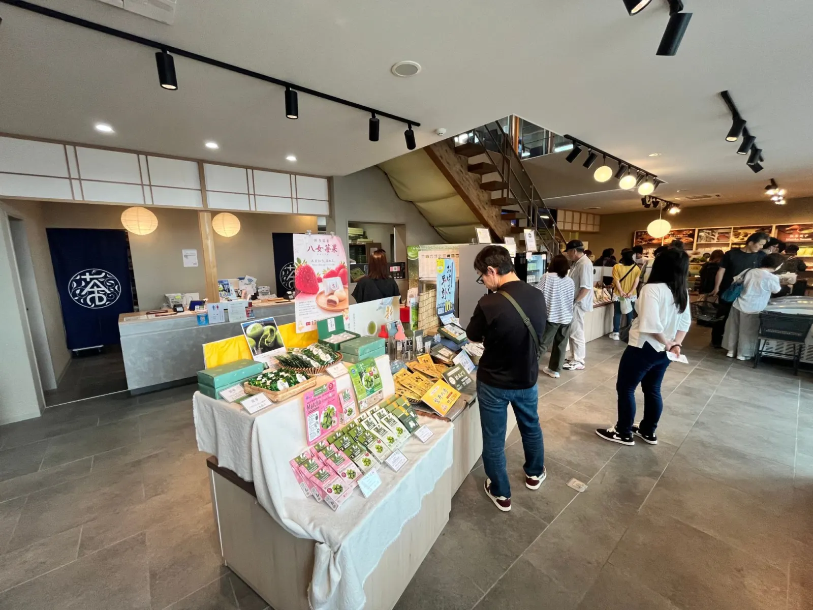 ภายในร้าน Ochamura ชั้น 1 มีโต๊ะวางขนมมัทฉะและชาญี่ปุ่น และบันไดไม้ขึ้นไปยังคาเฟ่
